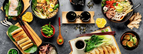 Karanlık arka planda çeşitli malzemeli Asya yemekleri. Üst görünüm.