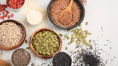 Variety of edible seeds on light background. Cereal and grains. Healthy food concept. Top view, flat lay, copy space