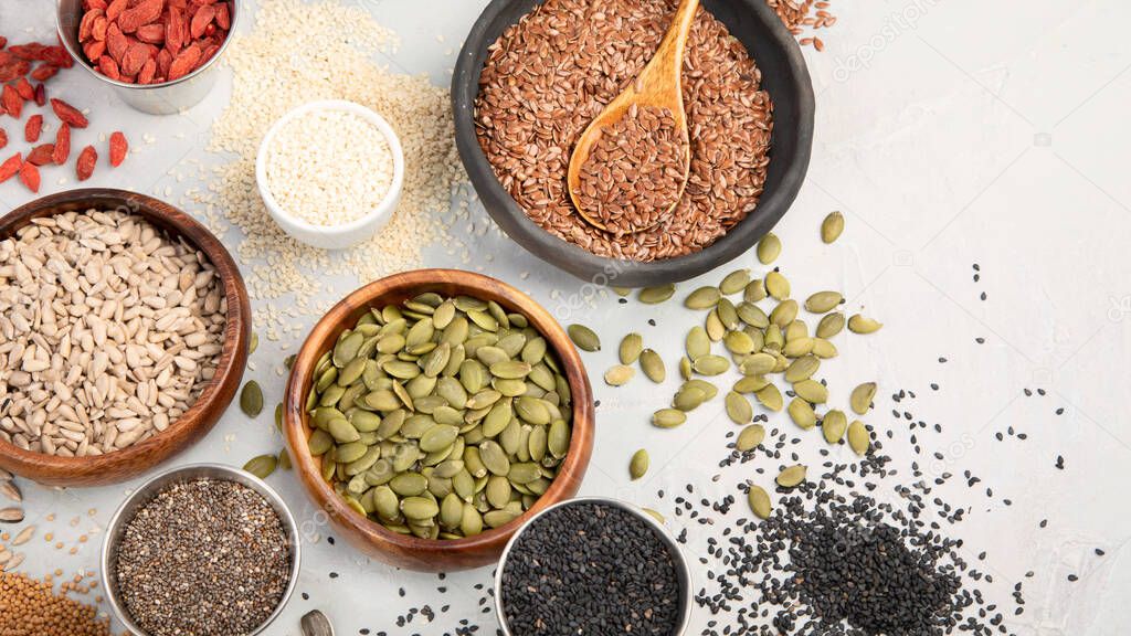 Variety of edible seeds on light background. Cereal and grains. Healthy food concept. Top view, flat lay, copy space