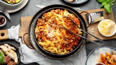 İtalyan yemekleri, makarna soslu makarna, mantı, tavuk soslu makarna, parmesan peyniri ve koyu arkaplanda su. Üst görünüm.