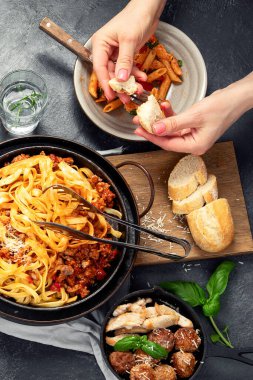 İtalyan yemekleri, makarna soslu makarna, mantı, tavuk soslu makarna, parmesan peyniri ve koyu arkaplanda su. Üst görünüm.