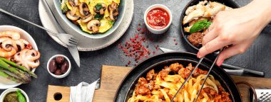 İtalyan yemekleri, makarna soslu makarna, mantı, tavuk soslu makarna, parmesan peyniri ve koyu arkaplanda su. Üst görünüm.