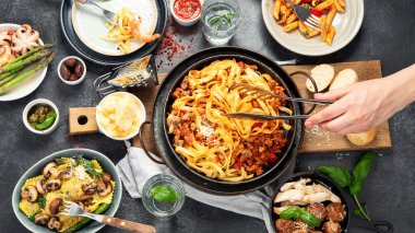 İtalyan yemekleri, makarna soslu makarna, mantı, tavuk soslu makarna, parmesan peyniri ve koyu arkaplanda su. Üst görünüm.