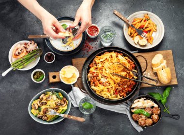 İtalyan yemekleri, makarna soslu makarna, mantı, tavuk soslu makarna, parmesan peyniri ve koyu arkaplanda su. Üst görünüm.