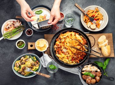 İtalyan yemekleri, makarna soslu makarna, mantı, tavuk soslu makarna, parmesan peyniri ve koyu arkaplanda su. Üst görünüm.