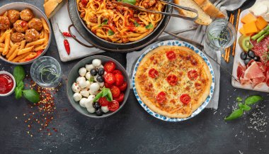 Koyu arka planda İtalyan yemek çeşitleri. Geleneksel gıda konsepti. Bulaşıklar ve aperatifler. Düz konum, üst görünüm, kopyalama alanı