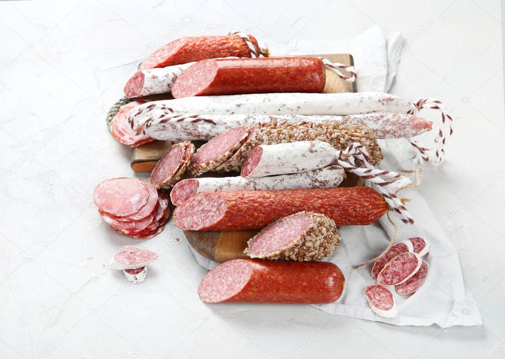 Sausages salami assortment on light background. Meat product made of finely chopped and seasoned meat. 