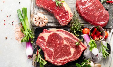 Baharatlı ve otlu lezzetli biftekler yapmak için taze çiğ et. Beyaz arka planda ızgara et için hazırlama, üst görünüm.