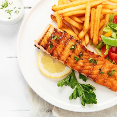 Sebzeli somon bifteği ve hafif arka planda patates kızartması. Taze ızgara. Sağlıklı bir akşam yemeği. Akdeniz diyeti. Üst görünüm, düz görünüm, kopyalama alanı