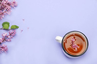 Renkli arka planda bir fincan çayla leylak çiçekleri. Atmosfer yaz konsepti. Üst görünüm, düz görünüm, kopyalama alanı