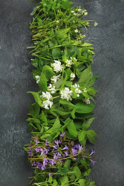 Edible plants and flowers on a dark background. Wild herbs as sources of carotenoids. Flat lay, top view, copy space