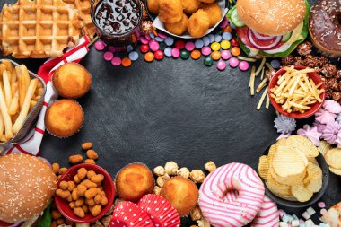 Sağlıksız ürünler. Yemek vücut, deri, kalp ve dişler için kötüdür. Fast karbonhidrat karışımı. Arka planda patates kızartması ve kola var. Kopyalama alanı olan üst görünüm.