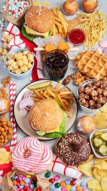 Various of american food, French fries, hamburgers, nuggets, hotdog, chips, popcorn, sauces on a white background, top view.