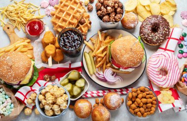 Various of american food, French fries, hamburgers, nuggets, hotdog, chips, popcorn, sauces on a white background, top view.