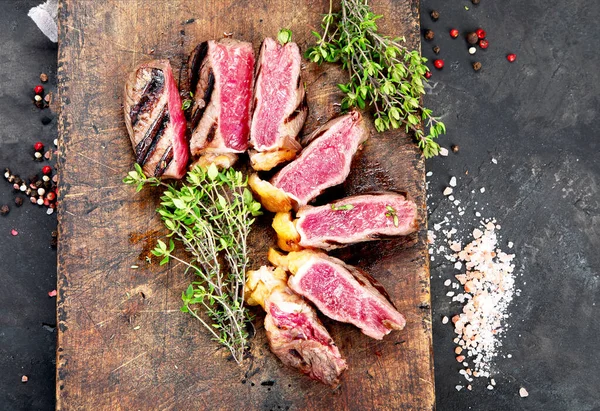 Grilled Beef Steaks Pepper Herbs Salt Cutting Board Dark Background — Stockfoto