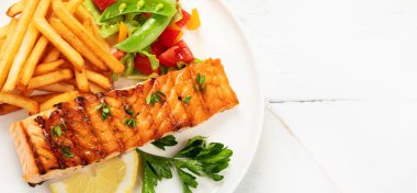 Sebzeli somon bifteği ve hafif arka planda patates kızartması. Taze ızgara. Sağlıklı bir akşam yemeği. Akdeniz diyeti. Üst görünüm, düz görünüm, kopyalama alanı, panorama