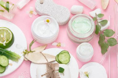 Pembe arka planda yüz ve vücut bakım ürünleri. Doğal kozmetikler. Üst manzara, düz uzanma