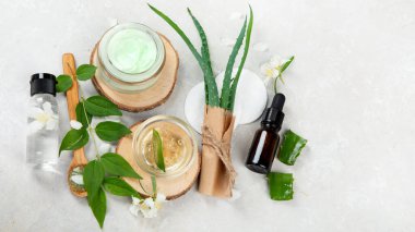 Aloe Vera arka planda nemlendirici ve dilimler. Güzellik tedavi konseptleri. Üst görünüm, düz görünüm, kopyalama alanı