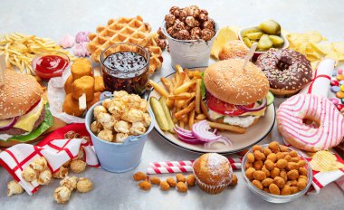 Various of american food, French fries, hamburgers, nuggets, hotdog, chips, popcorn, sauces on a white background, top view.