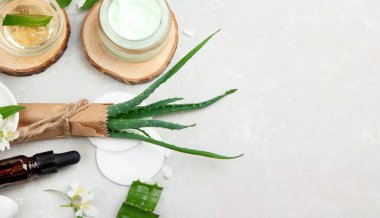 Aloe Vera arka planda nemlendirici ve dilimler. Güzellik tedavi konseptleri. Üst görünüm, düz görünüm, kopyalama alanı