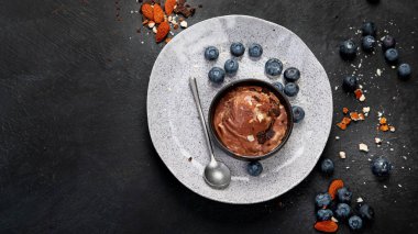 Chocolate ice cream with berries on dark background. Top view, copy space