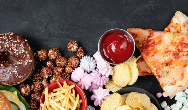 Unhealthy products. food bad for figure, skin, heart and teeth. Assortment of fast carbohydrates food with fries and cola on a dark background. Top view.