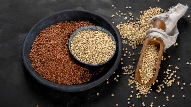 Raw green buckwheat on dark background. Food ingredients. Concept of organic food. 