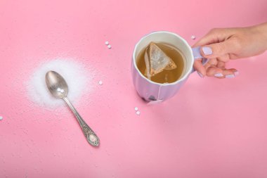 Cup of tea with sugar substitute on pink background. Healthy hot beverage. Top view, flat lay, copy space