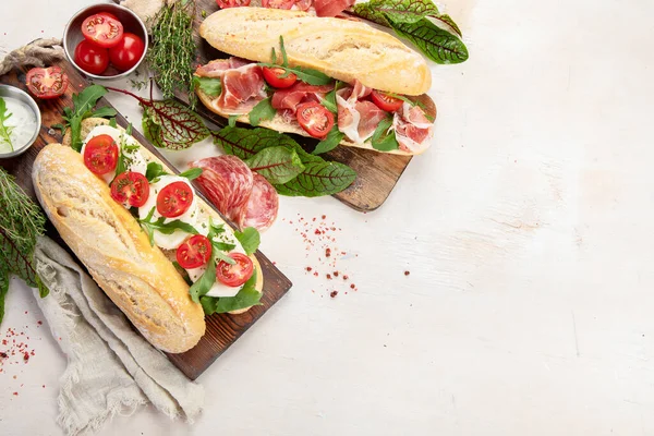 Two Baguette Sandwiches Salami Mozzarella Cheese Lettuce Tomatoes Ham Cutting —  Fotos de Stock