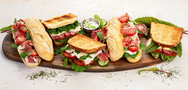 Assorted delicious baguette sandwiches. Various kinds of club sandwiches on a white background. Top view. Panorama.