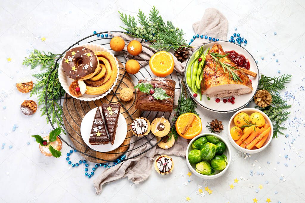 Delicious Christmas themed dinner table with roasted meat, potato, appetizers and desserts. Holiday concept. Top view on a grey background. Holiday concept.