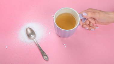 Cup of tea with sugar substitute on pink background. Healthy hot beverage. Top view, flat lay, copy space