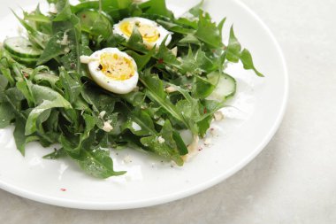 Fresh dandelion salad on light background. Edible plant and nectariferous. copy space
