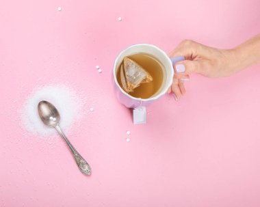 Cup of tea with sugar substitute on pink background. Healthy hot beverage. Top view, flat lay, copy space