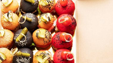 Small burgers on dark background. Appetizers idea. Event menu. Flat lay, top view, copy space
