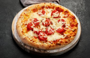 Freshly baked pizza on dark background. Tasty homemade food concept.