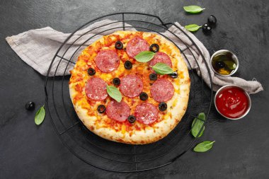 Freshly baked pepperoni pizza on dark background. Tasty homemade food concept. Top view, copy space