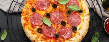 Koyu arkaplanda taze pişmiş pepperoni pizza. Lezzetli ev yapımı yemek konsepti. Üst manzara, panoramma