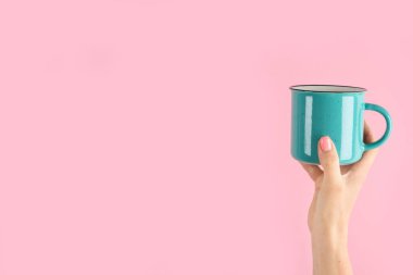 Kollarını kaldır ve pembe arka planda kahve fincanı tut. Kavramsal fotoğraf. Ön görünüm