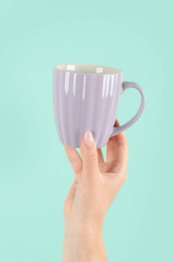 Yeşil arka planda çay fincanı tutan kollar havada. Kavramsal fotoğraf. Ön görünüm