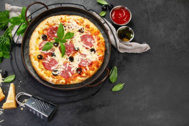 Freshly baked pepperoni pizza on dark background. Tasty homemade food concept. Top view, copy space