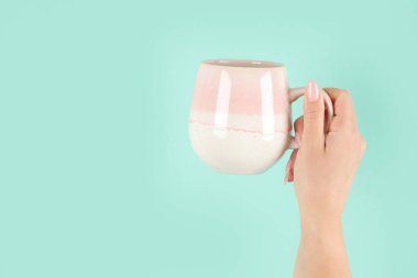 Yeşil arka planda çay fincanı tutan kollar havada. Kavramsal fotoğraf. Ön görünüm, boşluğu kopyala