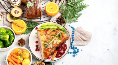 Delicious Christmas themed dinner table with roasted meat, potato, appetizers and desserts. Holiday concept. Top view on a grey background. Holiday concept.