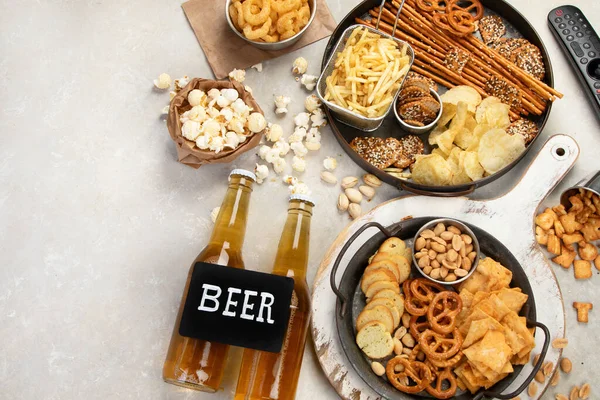 Assortment of beer and salty snacks on light background. Party food concept. Top view, copy space