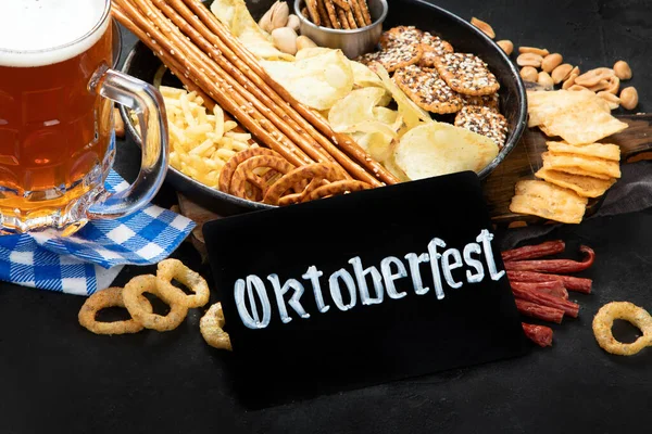 Assortment of beer and salty snacks on dark background. Party food concept.