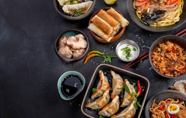 Geleneksel Asya yemekleri. Koyu arka planda çeşitli Asya yemekleri. Geleneksel yemeklerden oluşan çeşitli yemekler. Üst görünüm, alanı kopyala