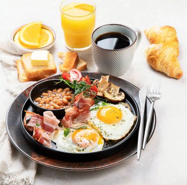 Yağda yumurta, sosis, pastırma ve gri arka planda tost ile tam İngiliz kahvaltısı.. 