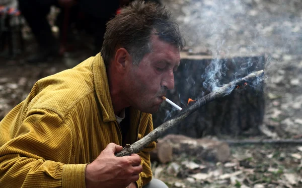 Adam yanan bir sopa ile bir sigara yakıyor — Stok fotoğraf