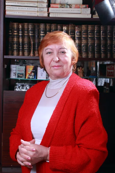 Woman against bookshelf — Stock Photo, Image