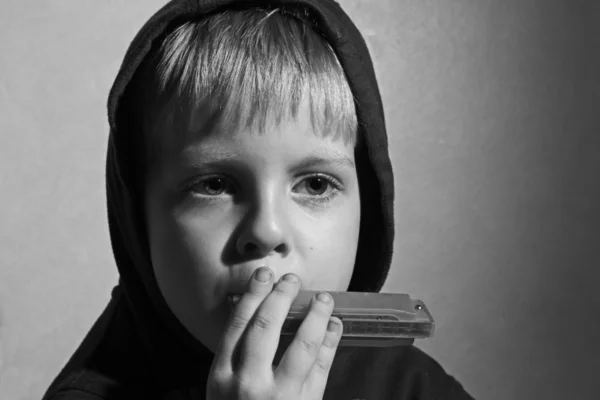 Junge mit der Kapuze spielt Mundharmonika — Stockfoto